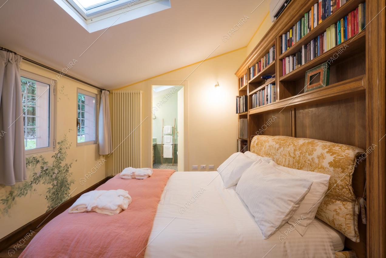 Camera da letto con lucernario e libreria a parete