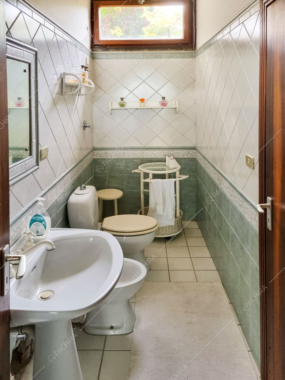Bagno con piastrelle bianche e verdi sulle pareti e sul pavimento