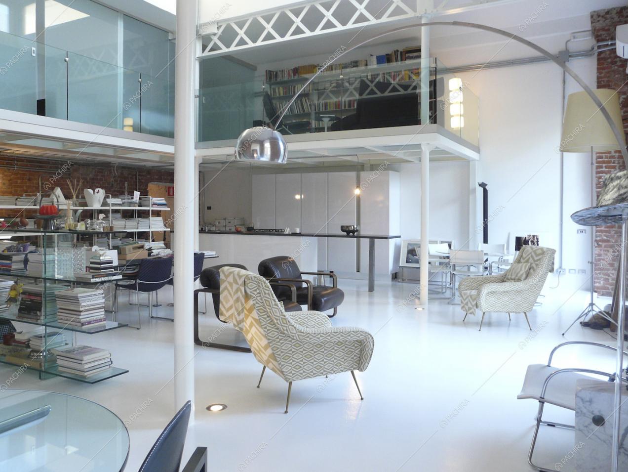 Salone con lampada e poltrone di design e vista sulla cucina con isola