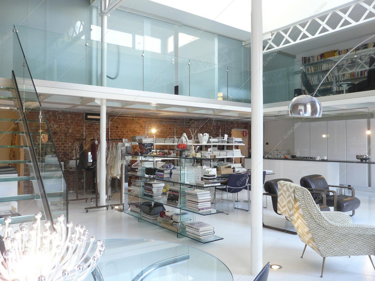 Dalle scale in vetro vista sul soppalco, sulla libreria che separa lo studio e sulla cucina