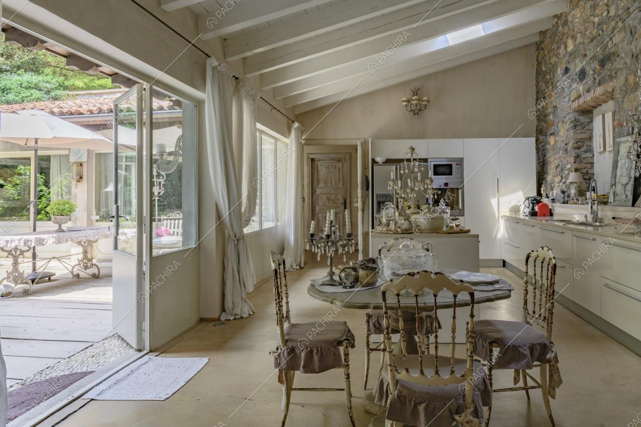 Tavolo da pranzo nella sala con cucina a vista e porta-finestra in metallo per accedere al giardino