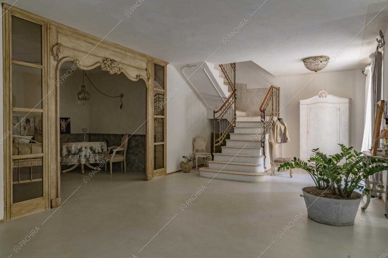 Atrio con vista sulle scale e sul salotto separato da vetrate con infissi in legno con boiserie