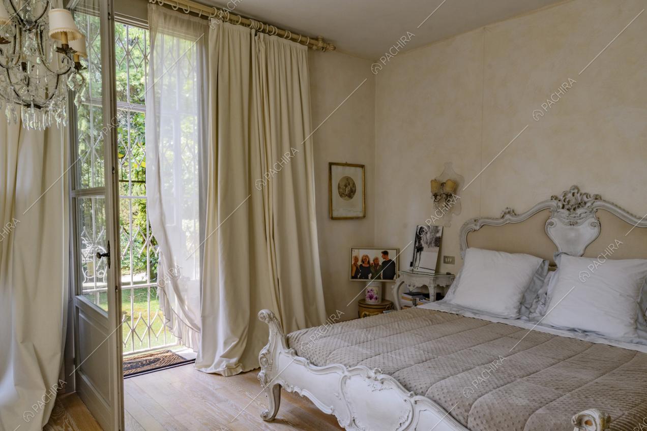 Camera da letto matrimoniale dalla struttura con boiserie, pavimento in parqiet e porta-finestra