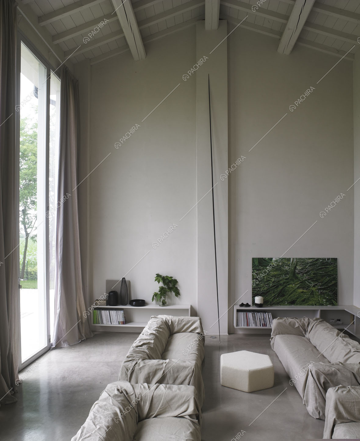 Travi bianche in legno a vista e pavimento in cemento lisciato nella zona living