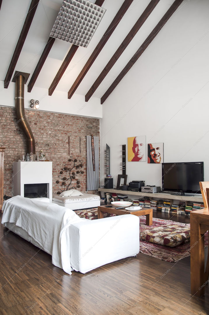 Zona living con divano, tappeti e soffitto con travi a vista