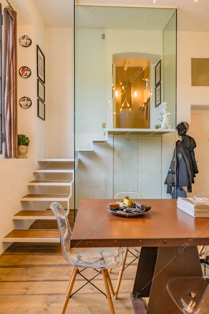 Dalla cucina con pavimento in parquet vista sulle scale con parete in vetro