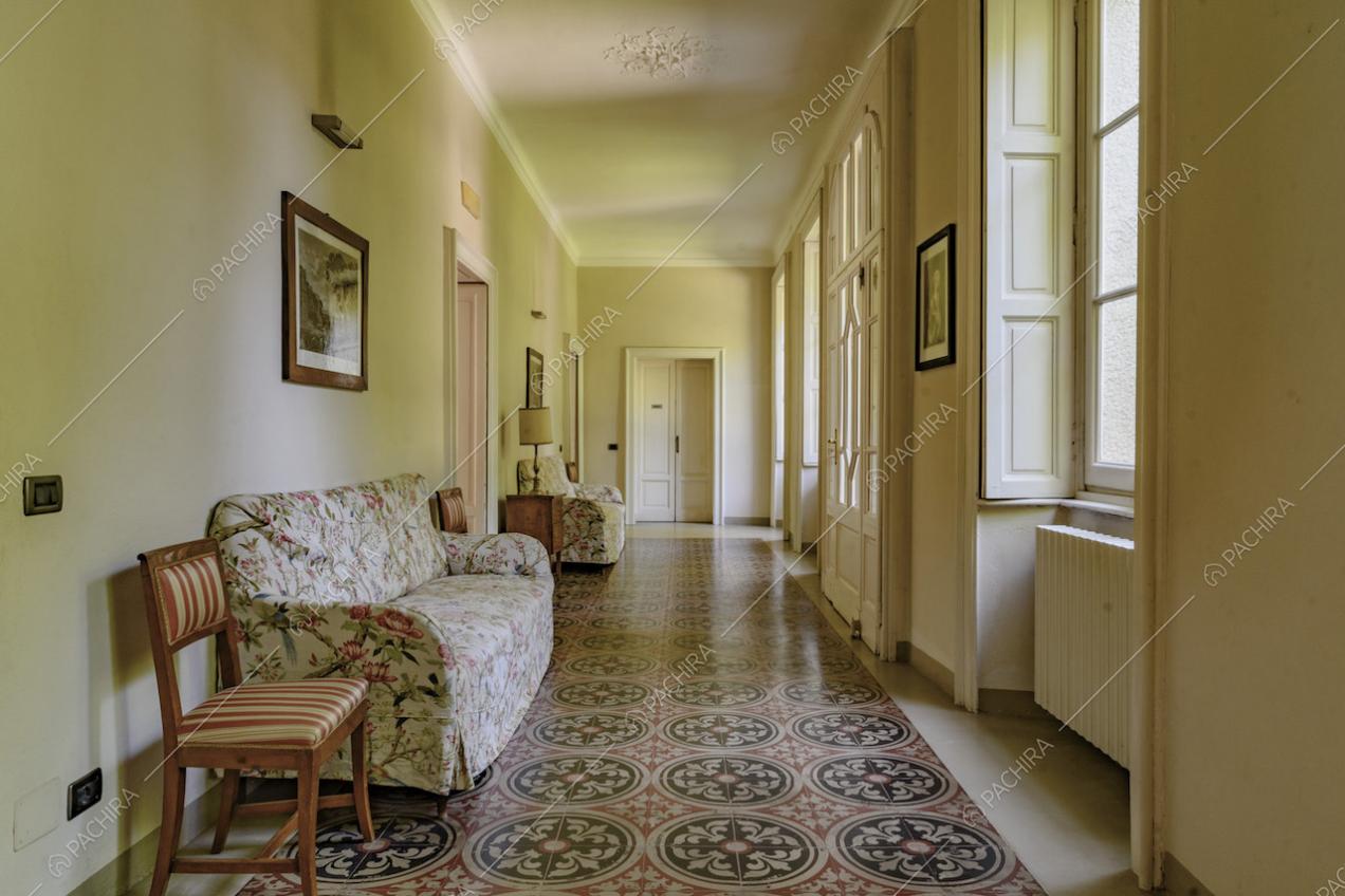 Ampio corridoio dalle pareti gialle, con pavimento in marmo e boiserie sul soffitto bianco