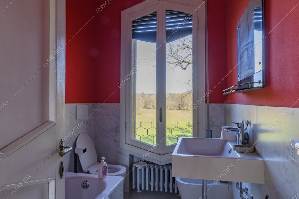 Bagno dalle pareti rosse e in marmo e vista sul parco