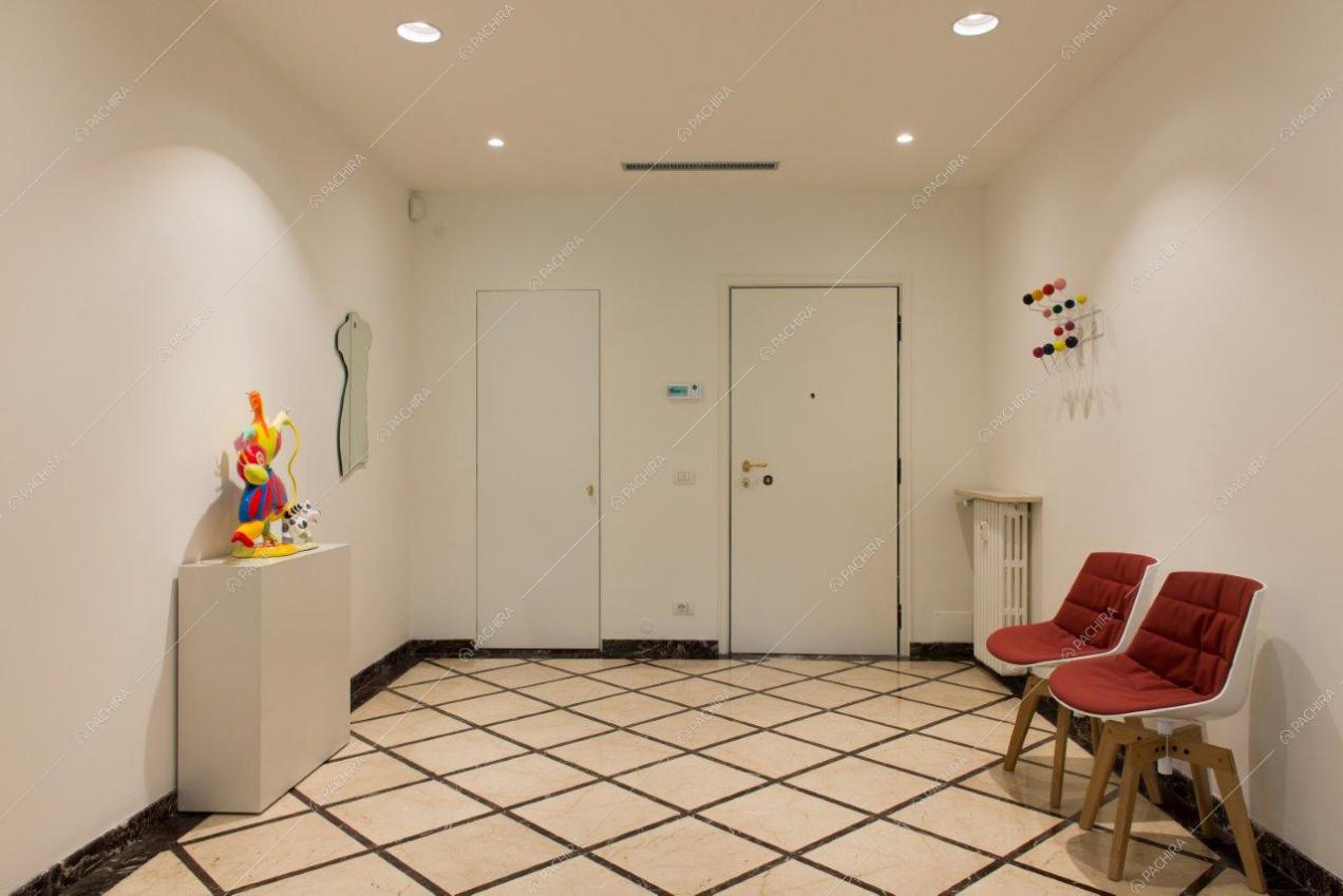 Ingresso dell'appartamento con pareti e soffitto bianchi e con sedie di design