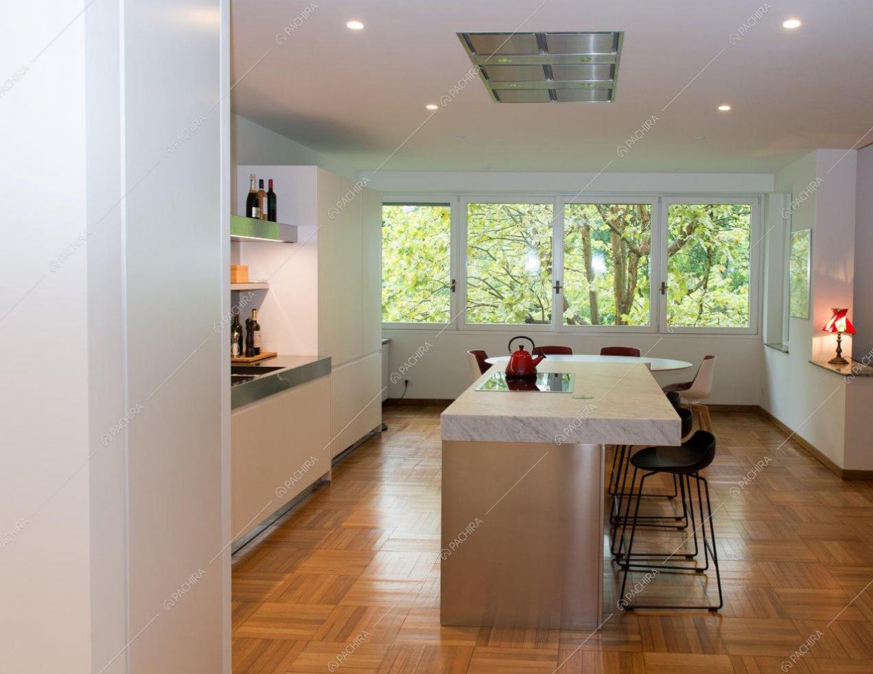 Isola con piano in marmo nella cucina con pavimento in parquet e ampie vetrate