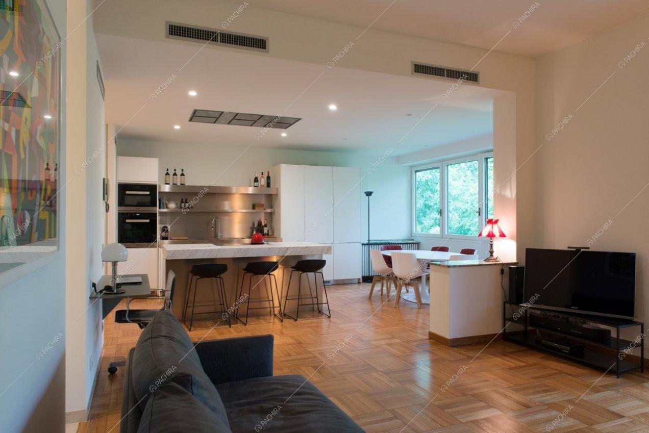 Cucina a vista dal salotto con pavimento in parquet e pareti e soffitto bianchi