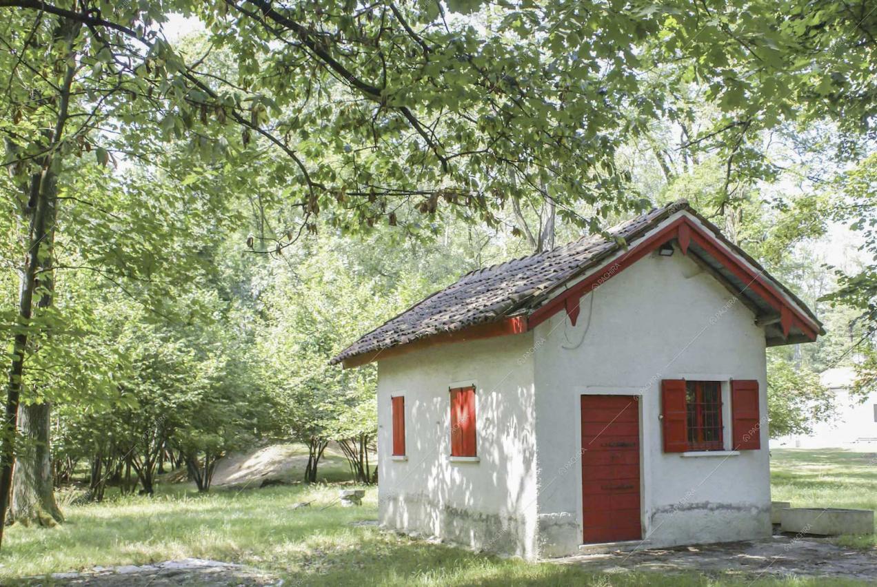 Dépendance bianca con porta e finestre rosse immersa nel parco
