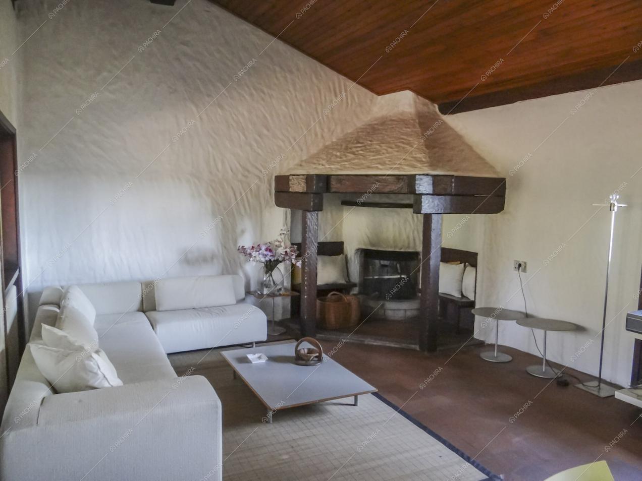 Salotto con camino, divano bianco angolare e soffitto in legno a vista