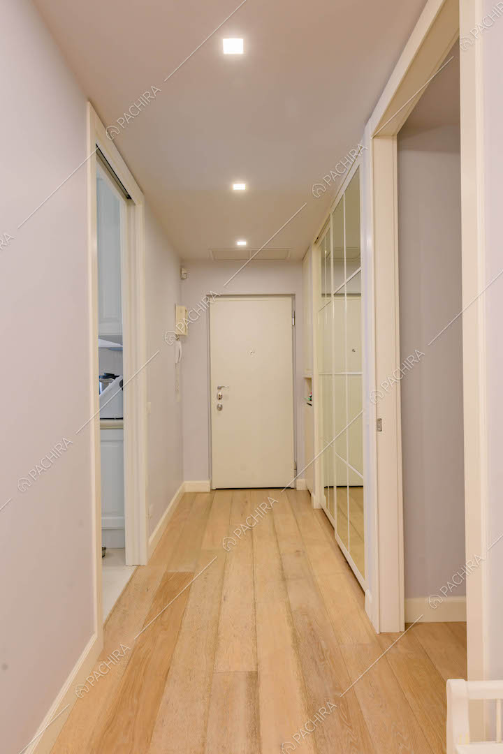 Corridoio con pavimento in parquet e vista su porta d'ingresso e cucina