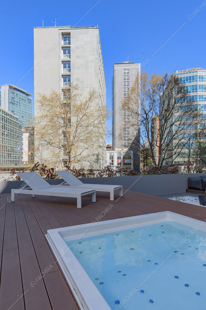 Idromassaggio e lettini bianchi sulla terrazza con pavimento in parquet da esterni