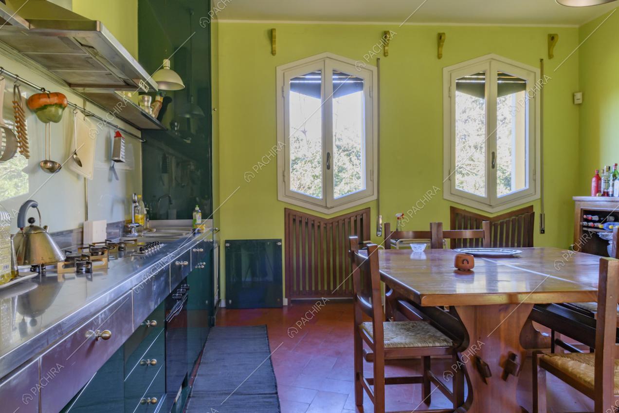 Cucina dalle pareti verde chiaro, pavimento in cotto e vista sul giardino