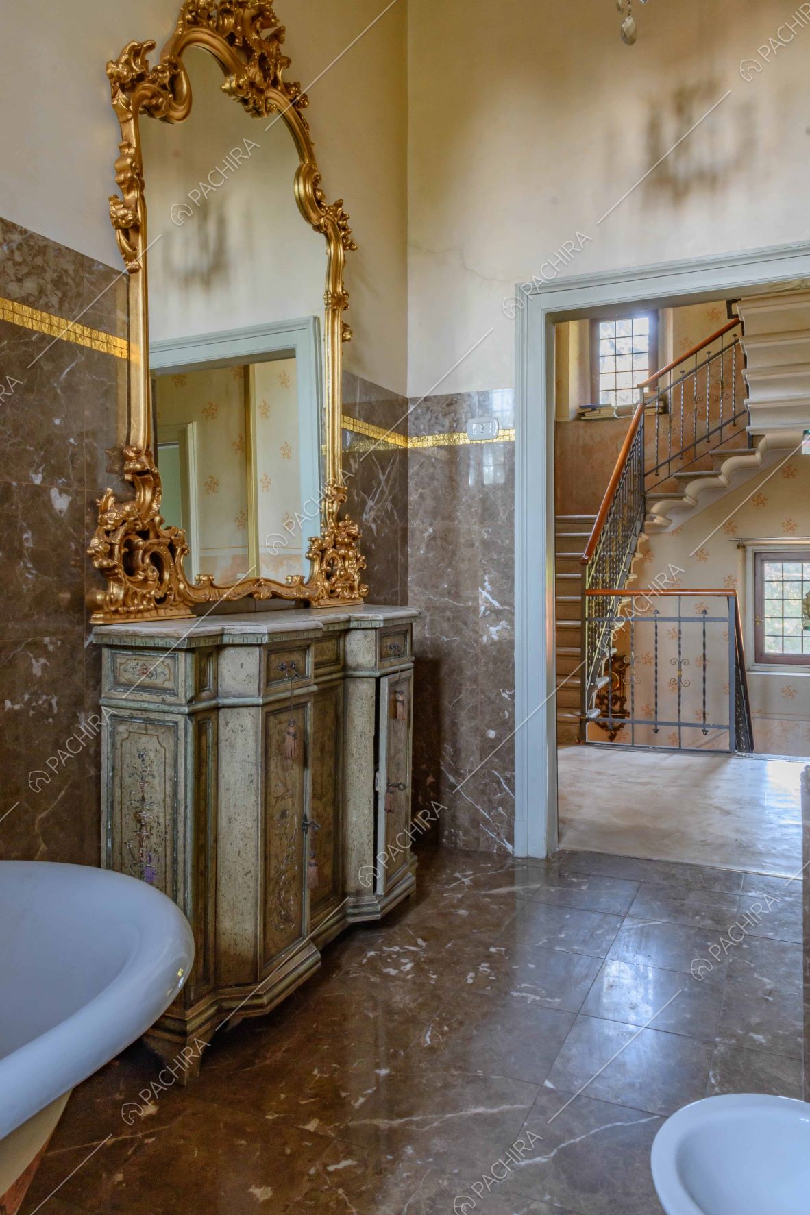 Dal bagno con le pareti e il pavimento in marmo marrone vista sulle scale