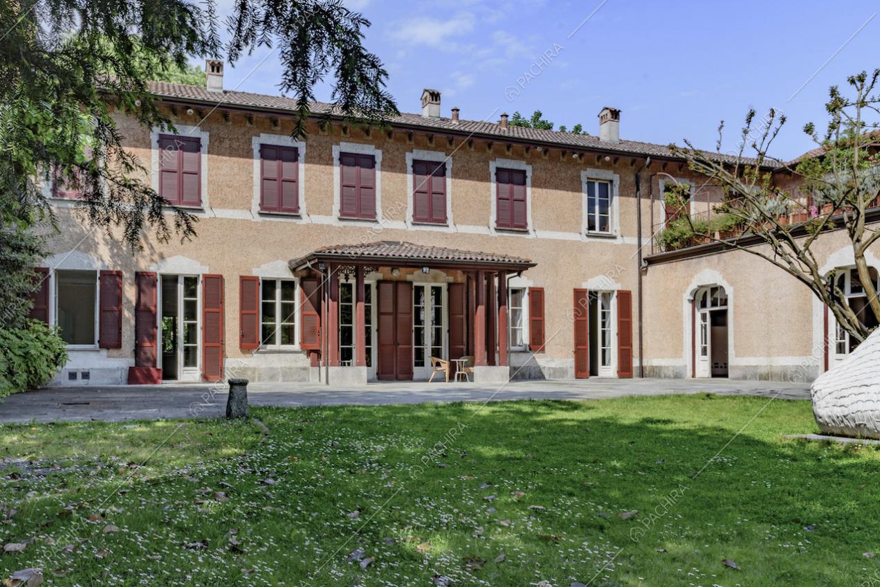 Dal giardino privato vista sull'ingresso della location con pergolato, persiane rosse e terrazza al primo piano