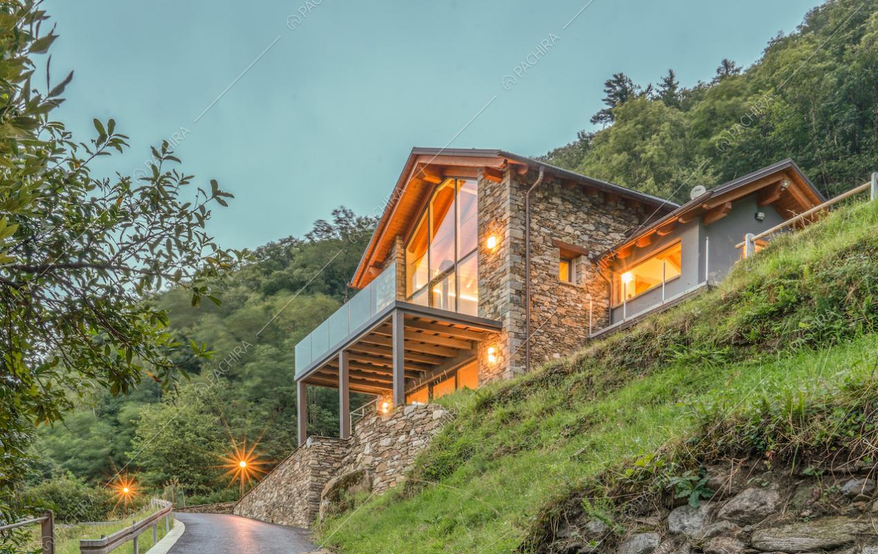 Dal giardino vista sulla villa con esterni in pietra, ampie vetrate e terrazza