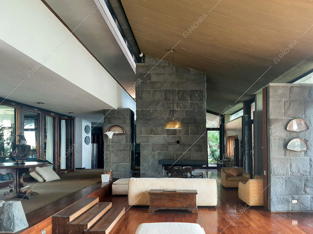 Pavimento in parquet, pareti in pietra a vista e grandi vetrate nella zona living