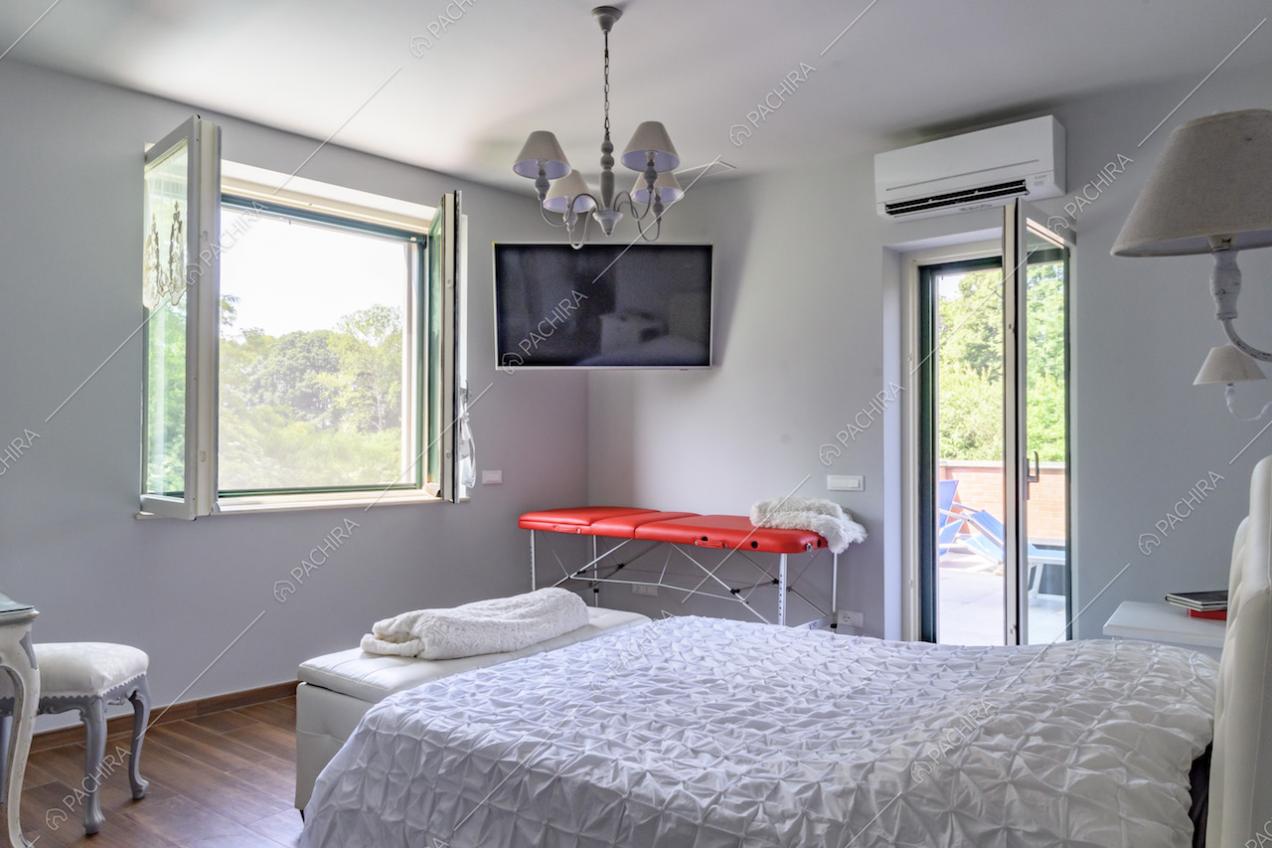 Camera da letto con pavimento in parquet, pareti grigie, televisione e porta-finestra