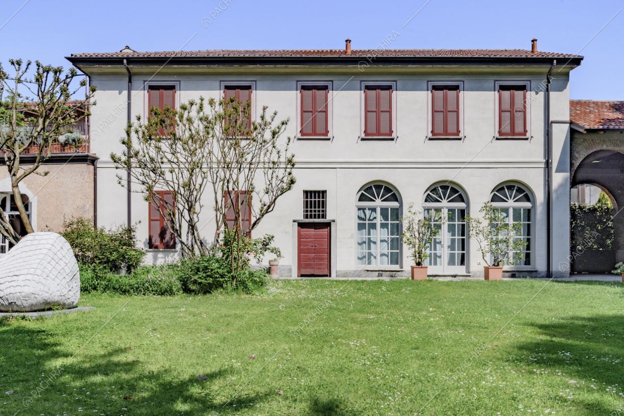 Facciata della dimora storica con porte-finestre bianche e persiane rosse, vista dal giardino