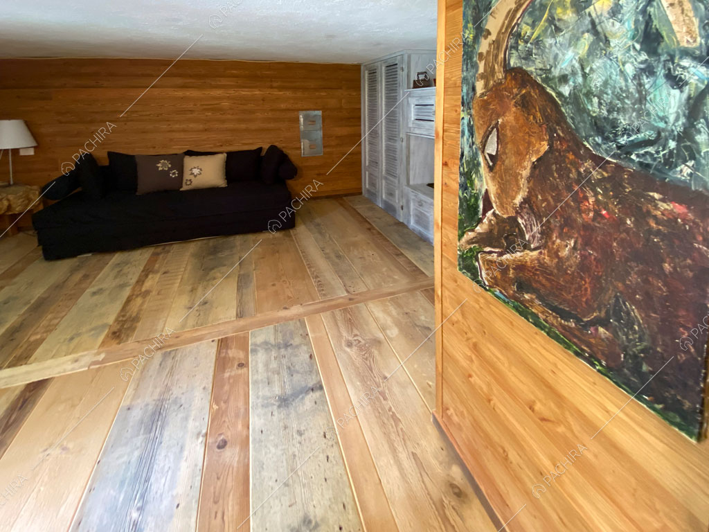 Pavimento in parquet nella sala con divano nero dello chalet Thar, location in stile rustico ad Aosta