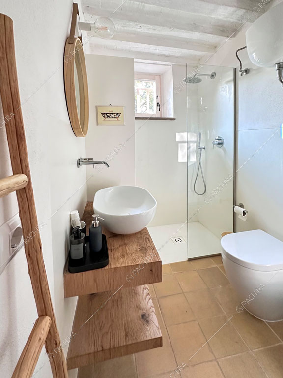 Luminoso bagno con box doccia, pareti bianche e ripiani in legno