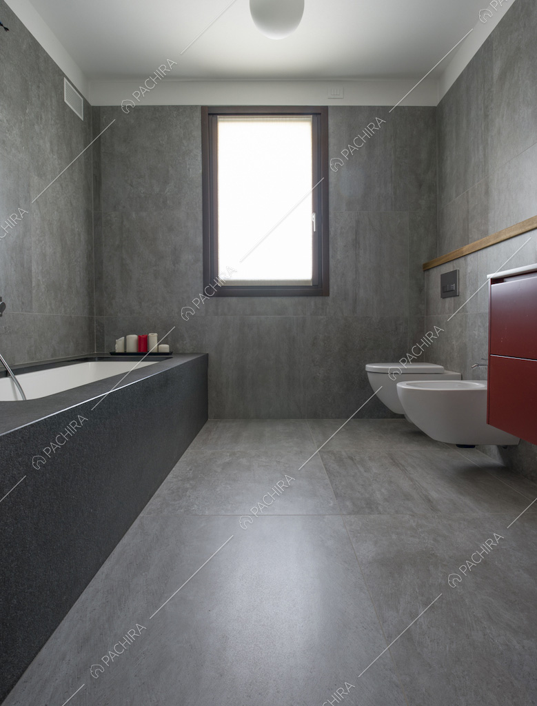 Bagno sui toni del grigio con pavimento e pareti in piastrelle e vasca da bagno