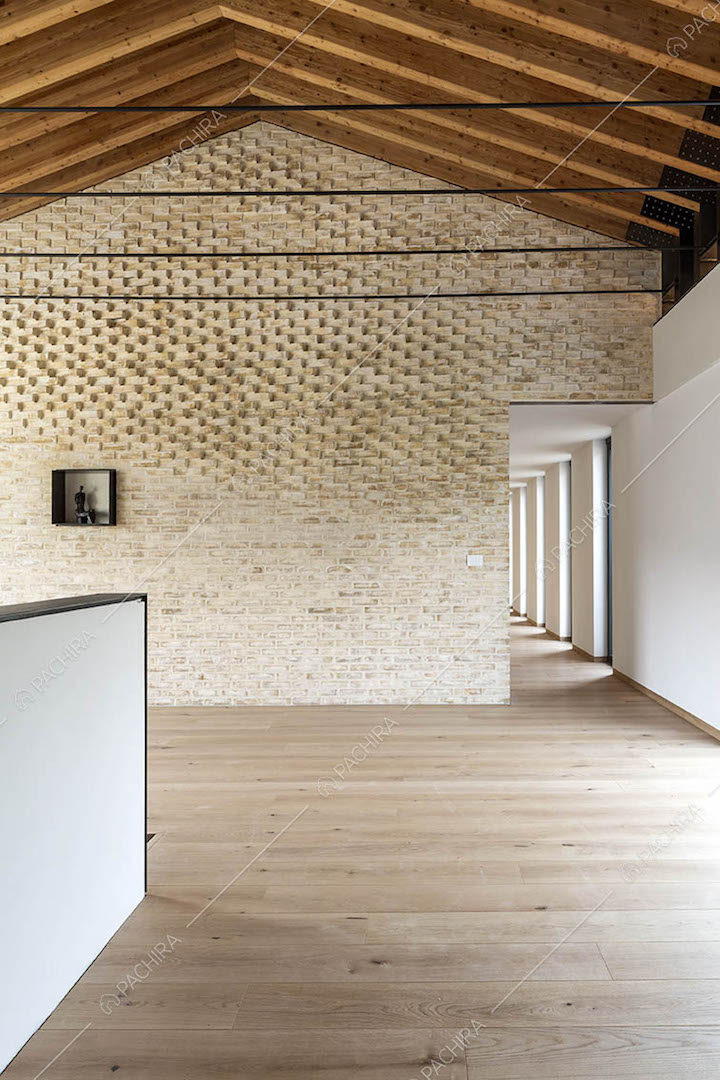 Stanza con pavimento in parquet, parete in mattoni a vista e travi in legno