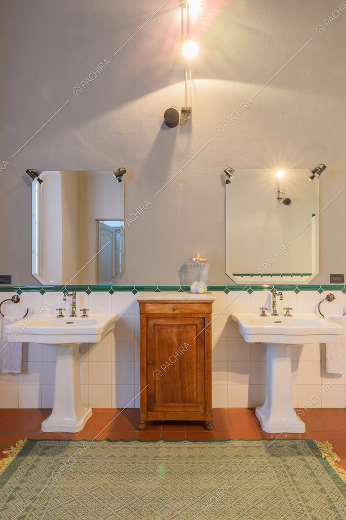 Ampio bagno con doppio lavandino, parete grigia e con piastrelle bianche