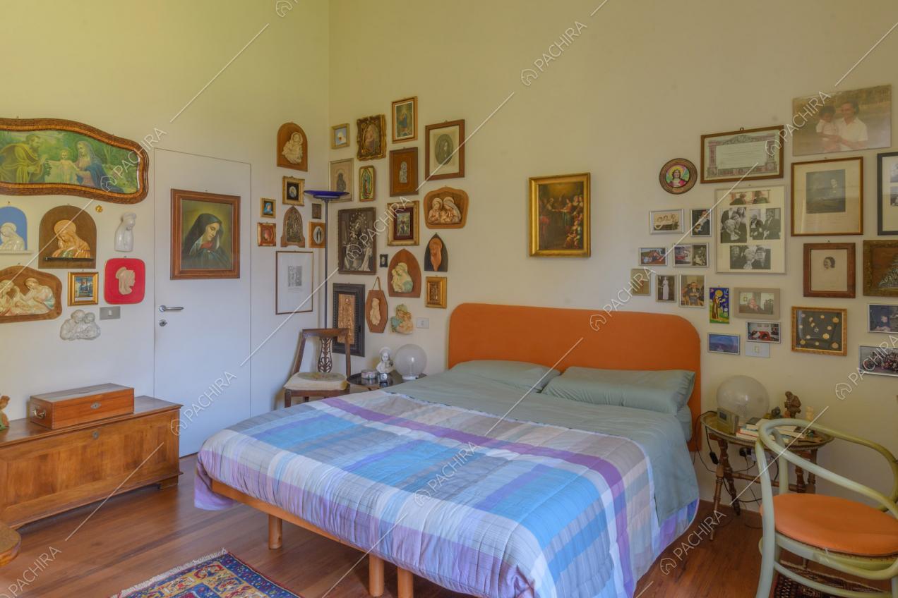 Letto matrimoniale nella luminosa camera con pavimento in parquet e pareti bianche