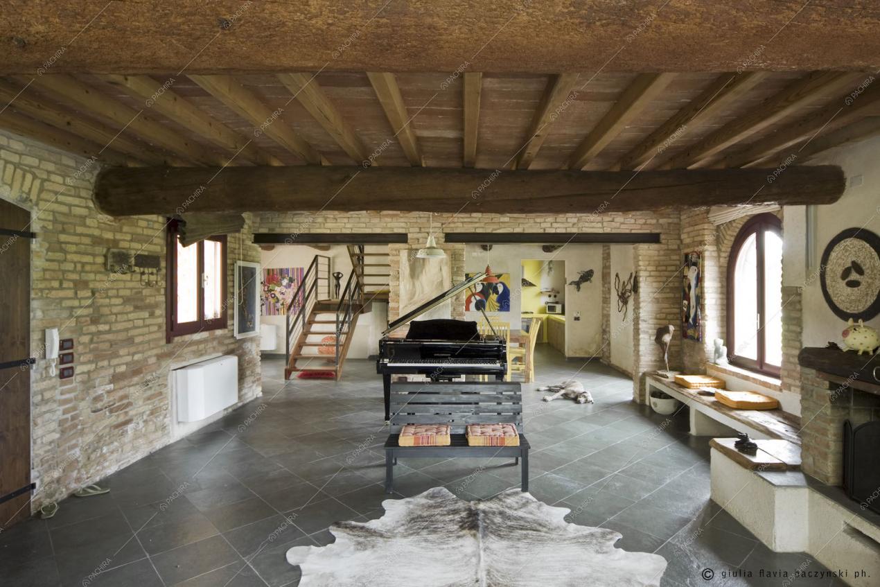 Pavimento a piastrelle, travi in legno a vista, panchina e pianoforte