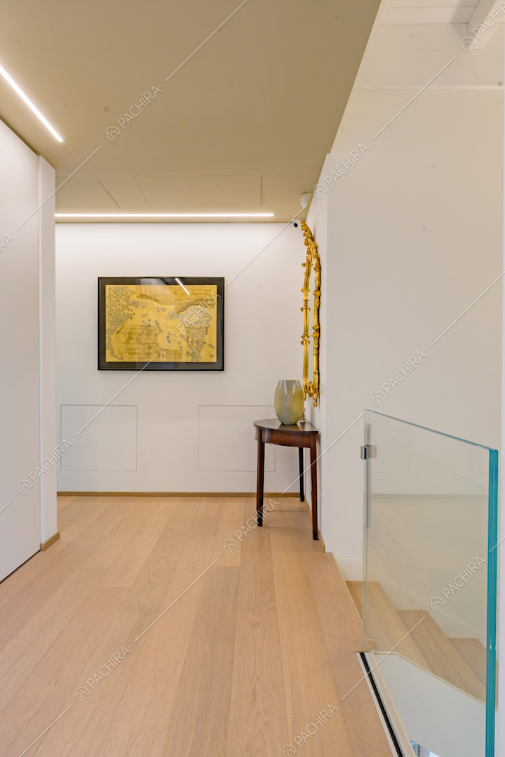 Pavimento in parquet, pareti bianche e scale con ringhiera in vetro