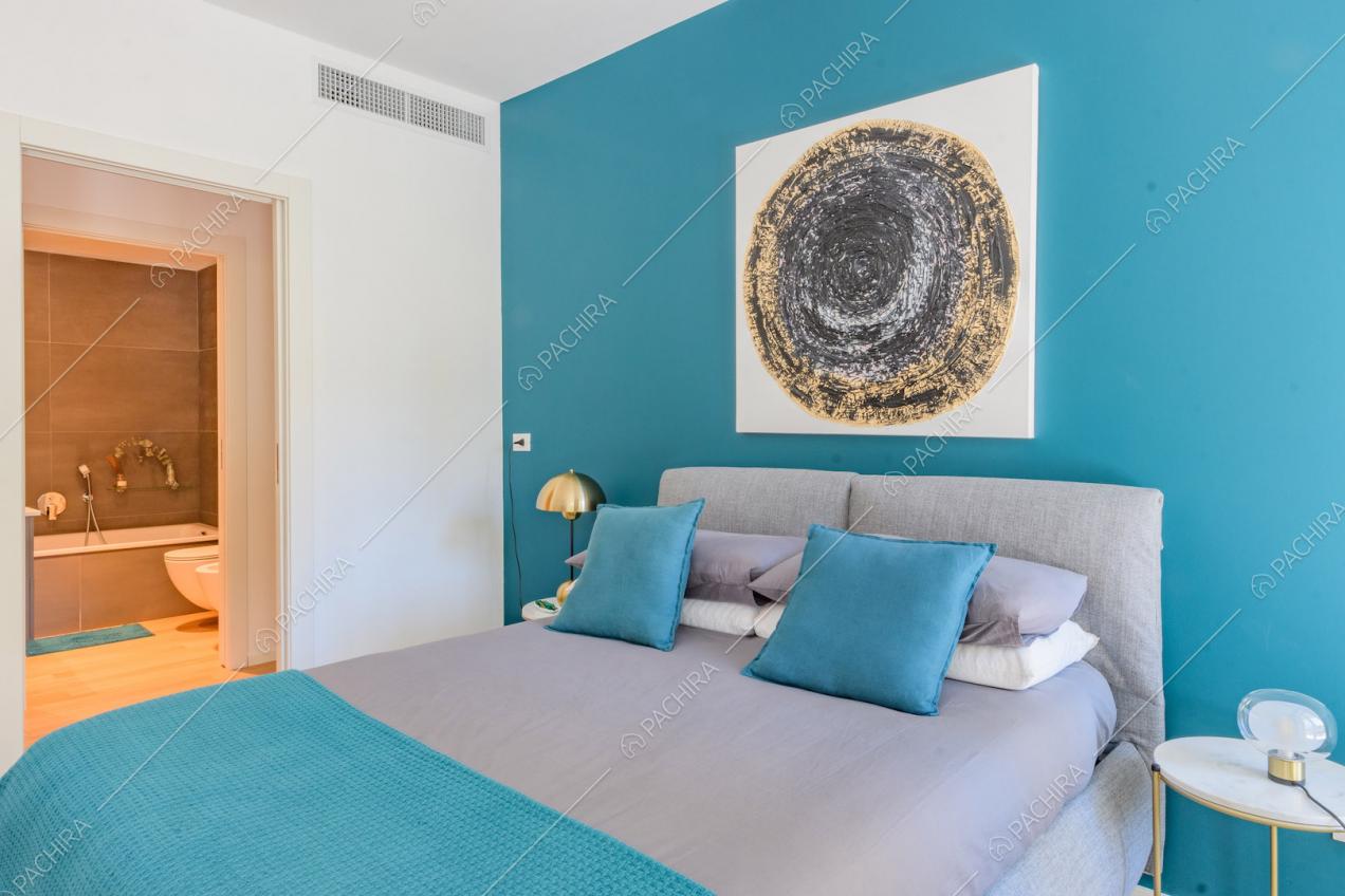 Letto matrimoniale nella luminosa camera con parete azzurra e bagno privato