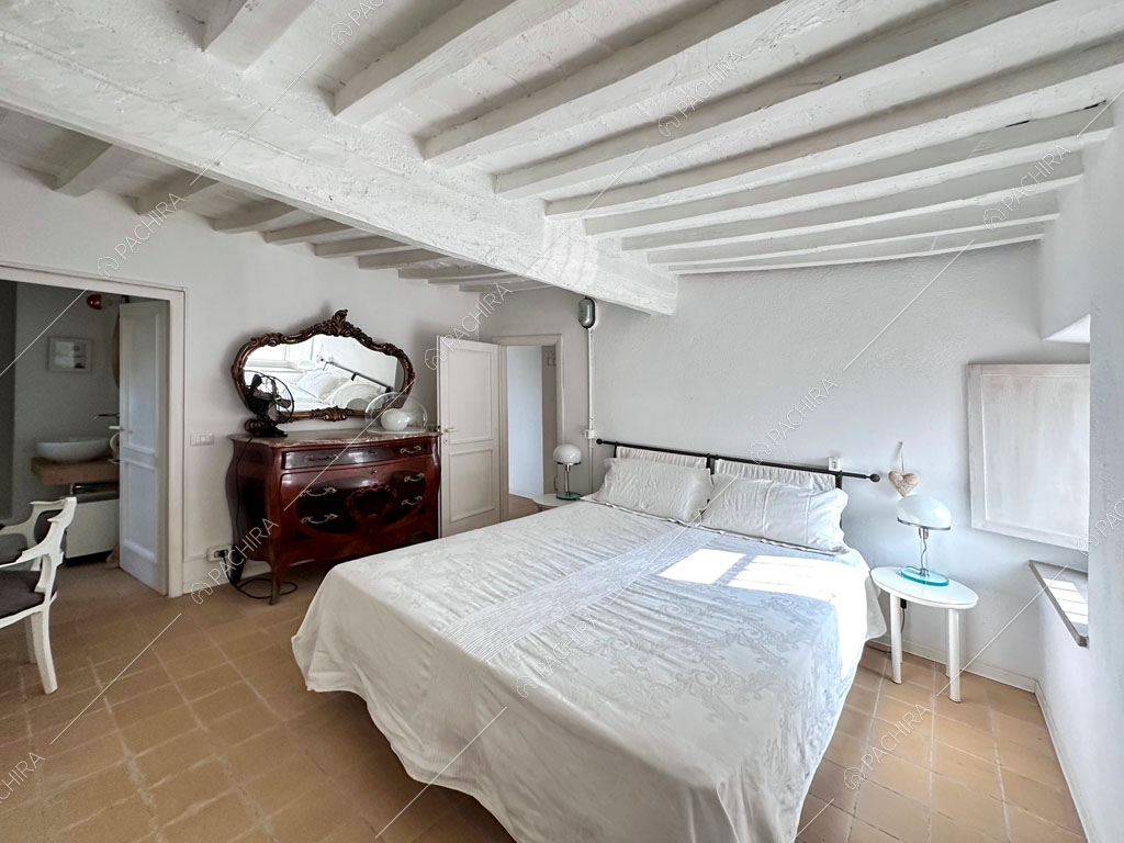 Travi bianche a vista sul soffitto nella camera da letto matrimoniale con bagno privato