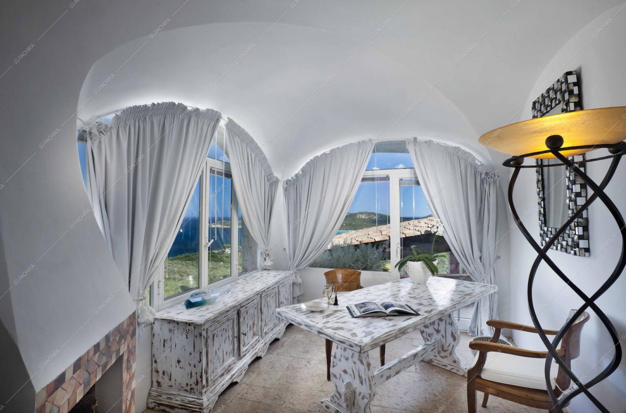 Armadietto e tavolo delabré in stanza con vetrate e soffitto a volte