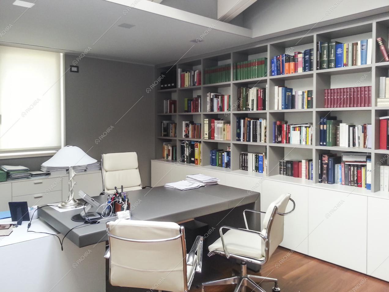 Studio con poltrone bianche e libreria a muro