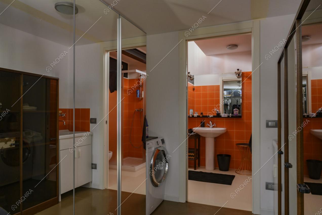 Piastrelle arancioni nel bagno e grandi specchi