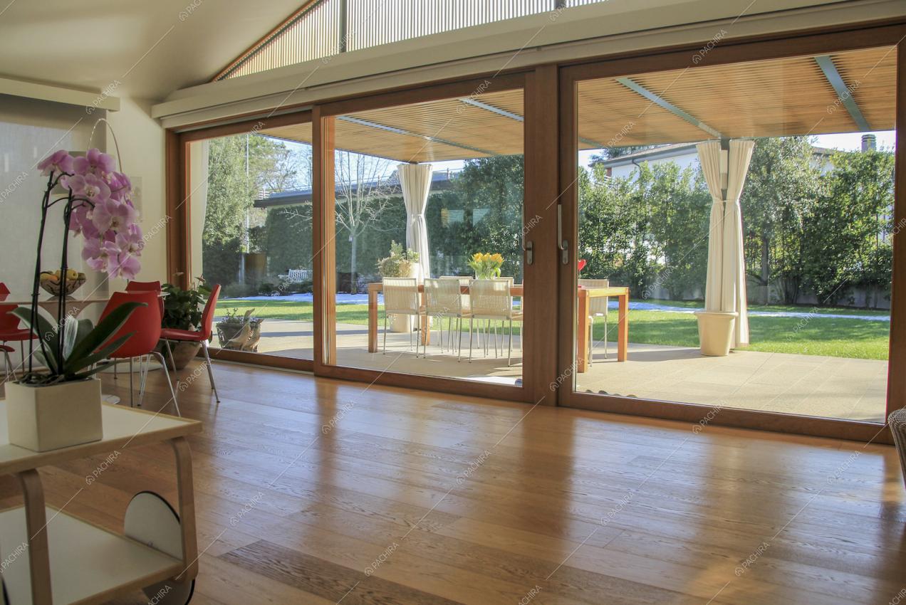 Pavimento in legno e ampie vetrate con vista sul giardino