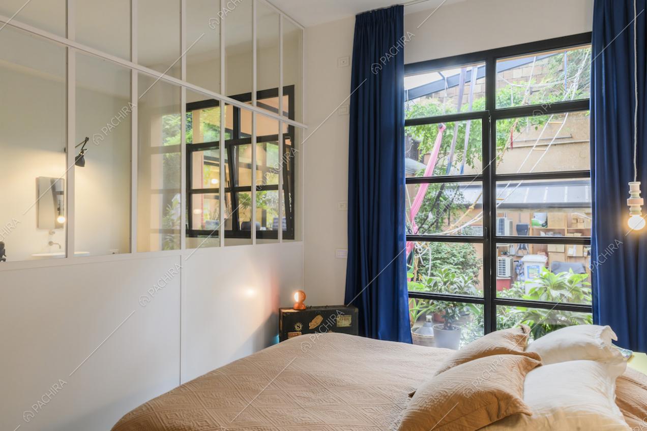 Camera da letto matrimoniale con vetrate bianche che si affacciano sul bagno