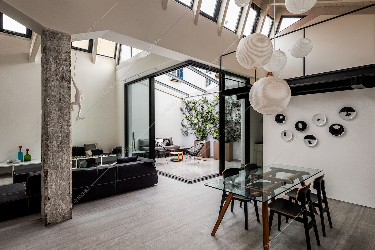 Sala con tavolo da pranzo con piano in vetro, lampadario bianco di design e giardino d'inverno