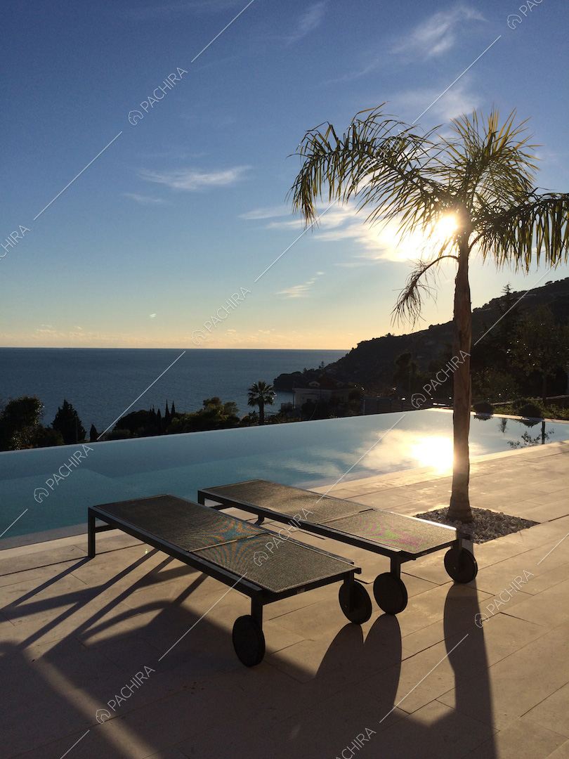 Lettini neri e palma sulla splendida terrazza con piscina vista mare