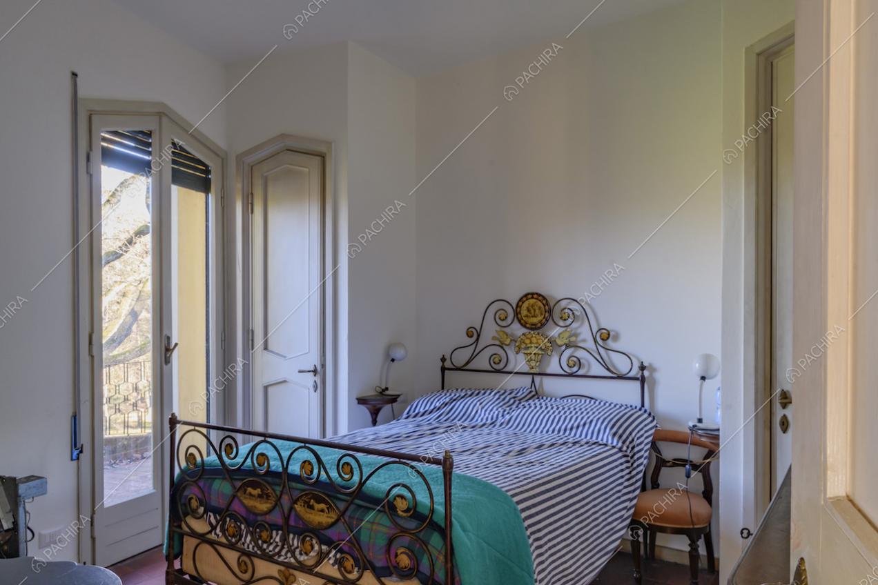 Camera da letto dalle pareti bianche e con accesso al balcone tramite porta-finestra