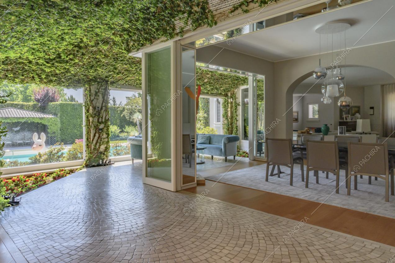 Veranda con rampicanti sul soffitto, pavimento in piastrelle e vista sulla sala da pranzo