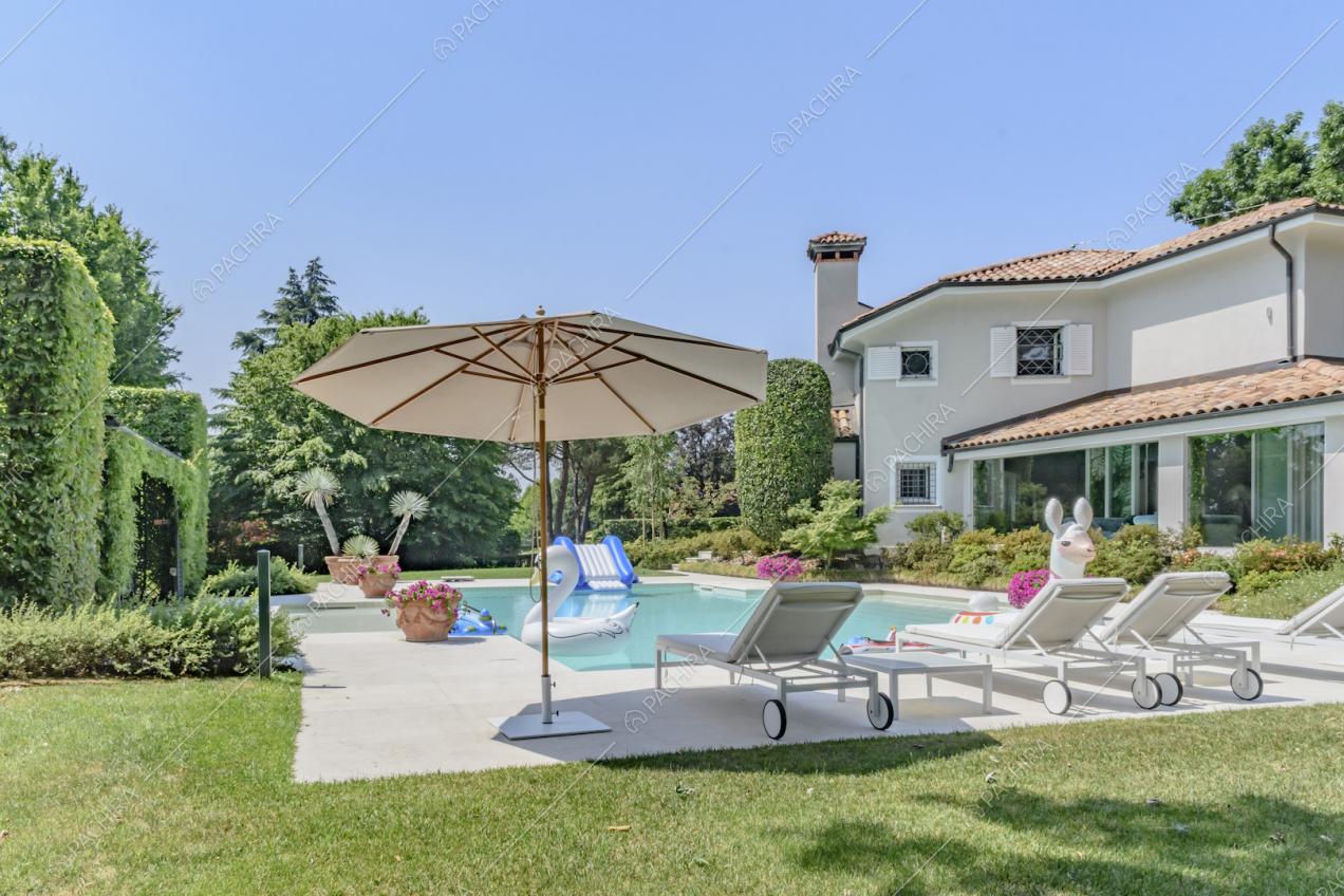 Nel giardino, piscina della location con lettini e vista sugli esterni grigi della villa