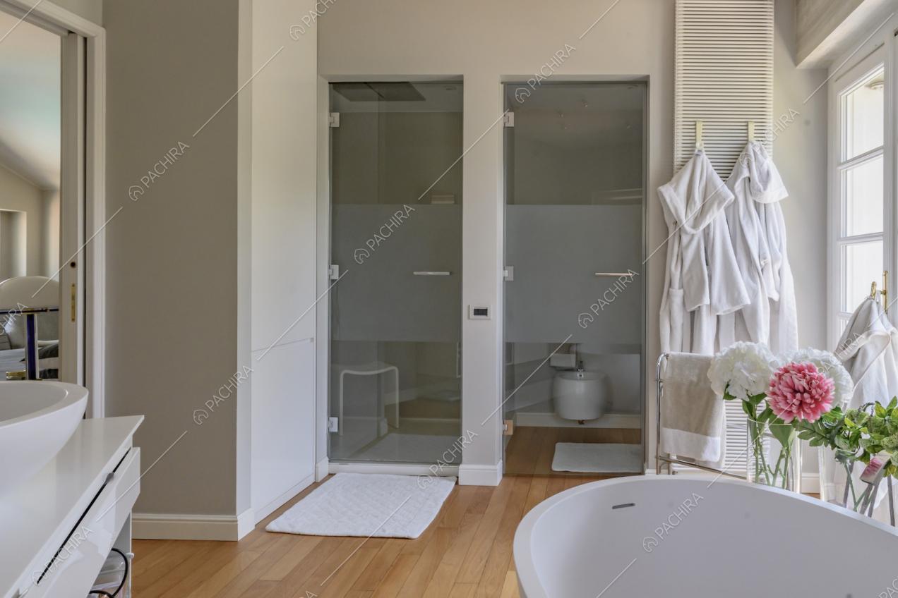 Dalla vasca da bagno vista su due porte a vetri con sanitari e doccia