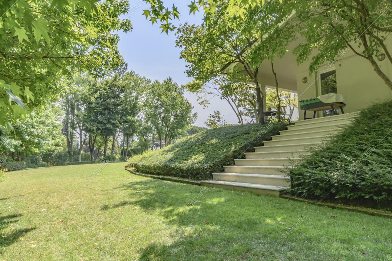 Dal giardino curato, scale bianche per accedere alla villa