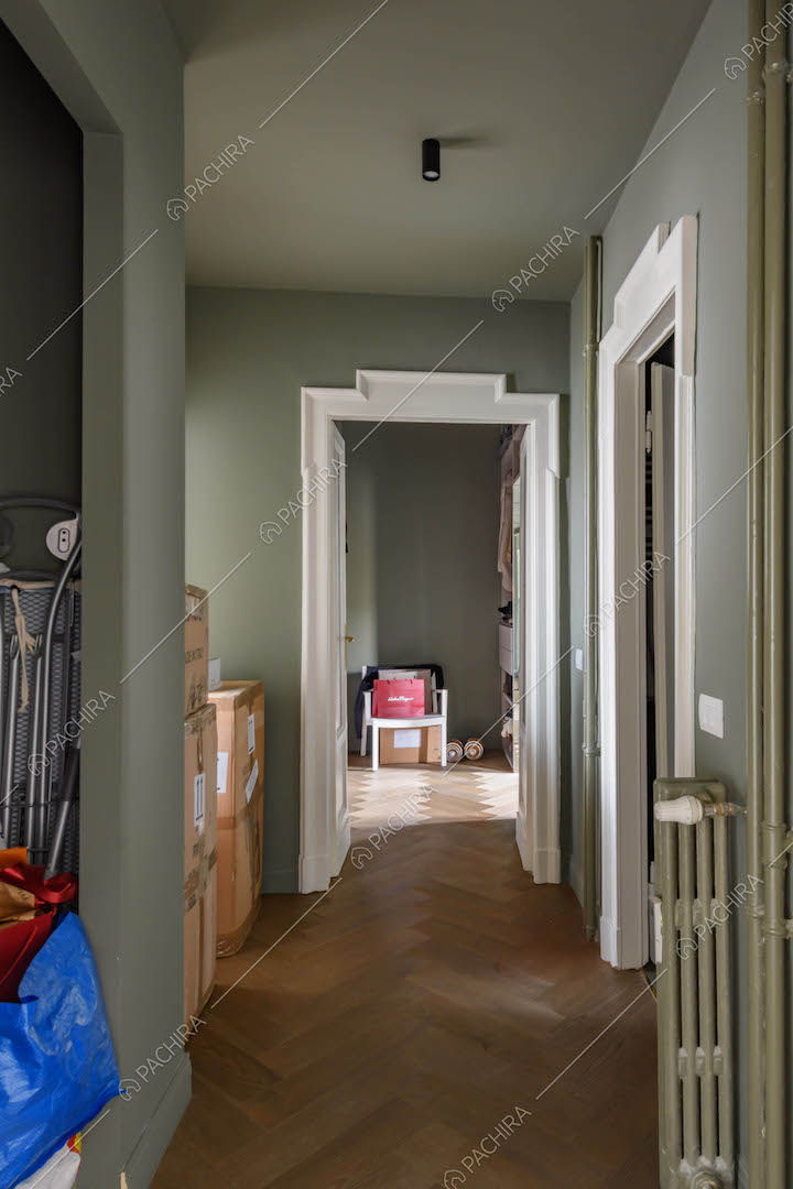 Corridoio con pareti verdi, cornice delle porte con boiserie e pavimento in parquet a spina di pesce
