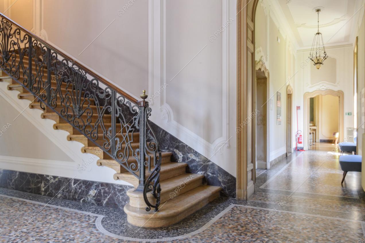 Scalone e vista sul corridoio dall'alto soffitto con boiserie